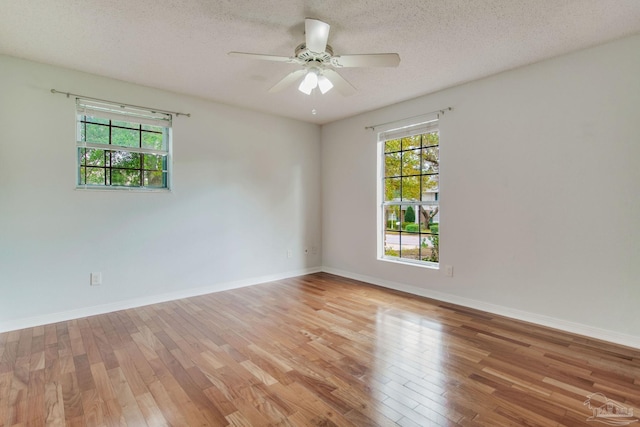 spare room featuring a textured ceiling, light wood-type flooring, and ceiling fan