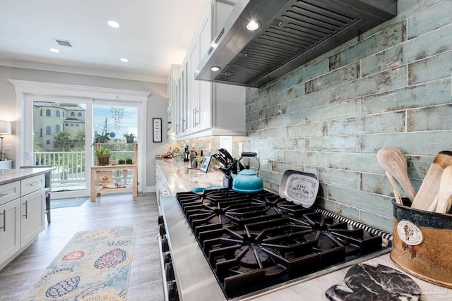 kitchen featuring gas stovetop, light hardwood / wood-style floors, custom exhaust hood, light stone counters, and white cabinets