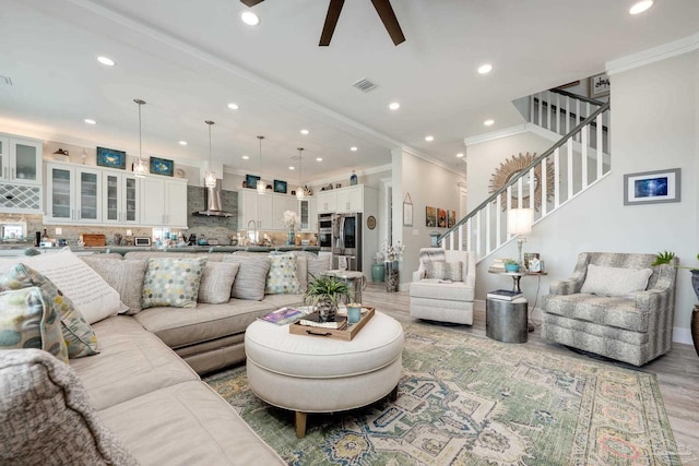 living room featuring crown molding, ceiling fan, and light hardwood / wood-style floors