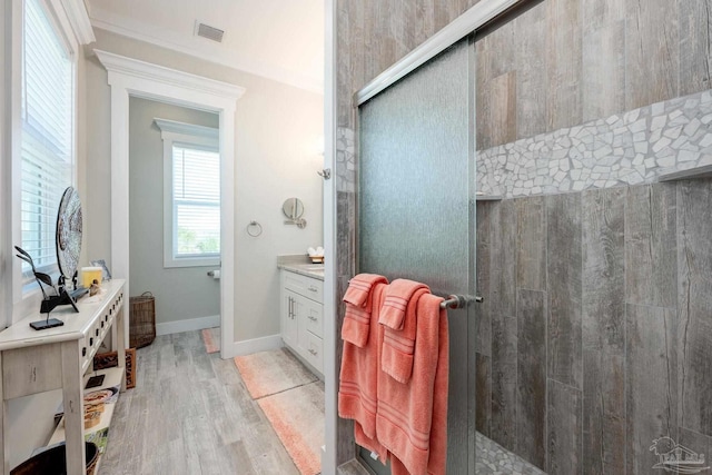 bathroom with crown molding, vanity, wood-type flooring, and an enclosed shower