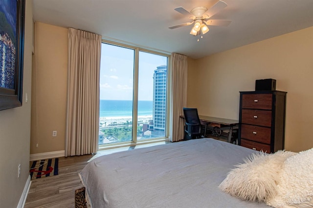 bedroom with light hardwood / wood-style floors, ceiling fan, and a water view