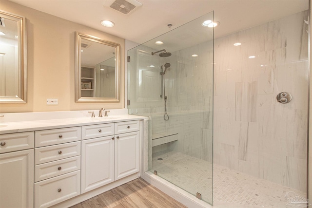 bathroom featuring a tile shower, vanity, and wood-type flooring