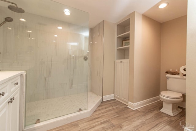 bathroom with tiled shower, hardwood / wood-style flooring, toilet, and vanity