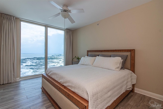 bedroom with hardwood / wood-style floors, a wall of windows, and ceiling fan