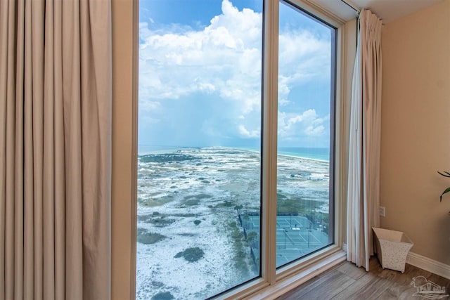 doorway to outside featuring hardwood / wood-style floors, a beach view, and a water view