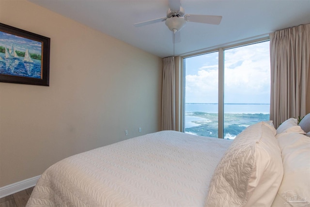 bedroom with ceiling fan, hardwood / wood-style flooring, and a water view