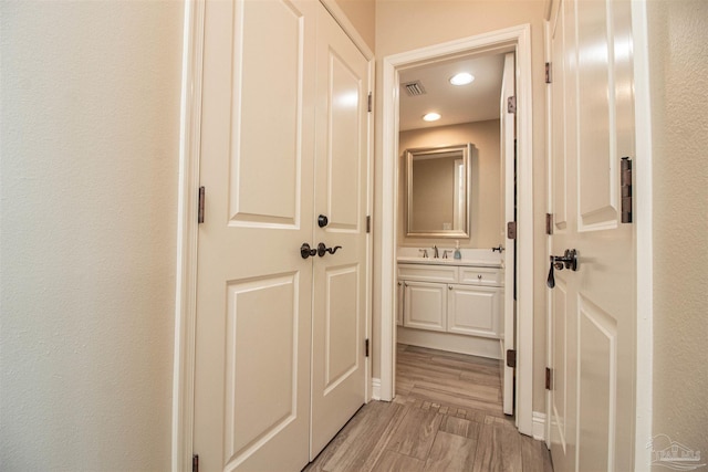 corridor featuring light wood-type flooring and sink