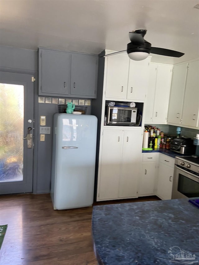 kitchen featuring ceiling fan, appliances with stainless steel finishes, white cabinetry, dark hardwood / wood-style flooring, and decorative backsplash