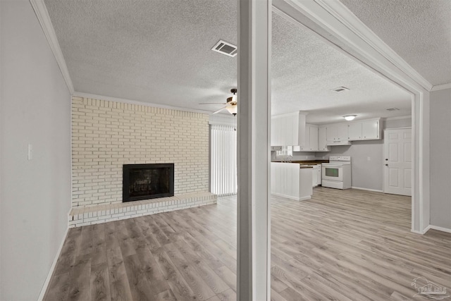 unfurnished living room featuring a textured ceiling, light wood-type flooring, and crown molding