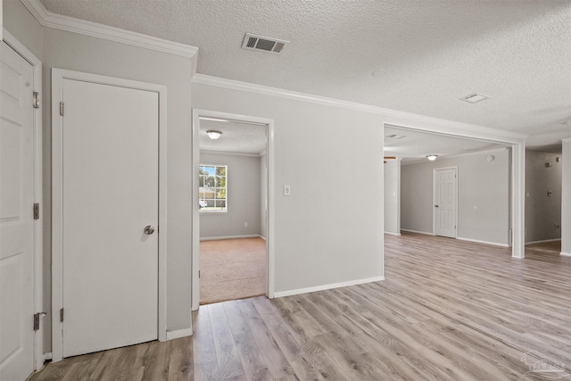 empty room featuring ornamental molding, light hardwood / wood-style flooring, and a textured ceiling