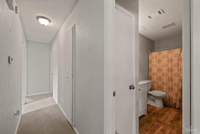 corridor featuring light hardwood / wood-style floors and a textured ceiling