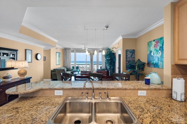 kitchen with open floor plan, crown molding, light stone countertops, and a sink