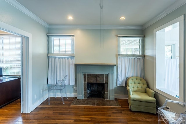 sitting room featuring baseboards, a tiled fireplace, wood finished floors, crown molding, and recessed lighting