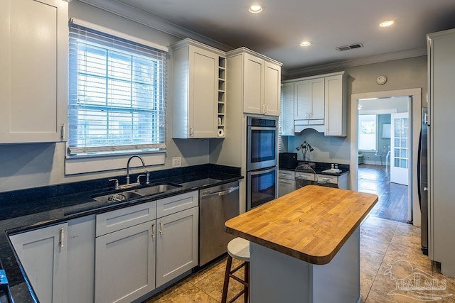 kitchen featuring a sink, visible vents, wooden counters, ornamental molding, and appliances with stainless steel finishes