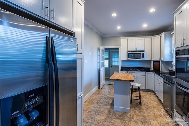 kitchen with recessed lighting, stainless steel appliances, a sink, wooden counters, and ornamental molding