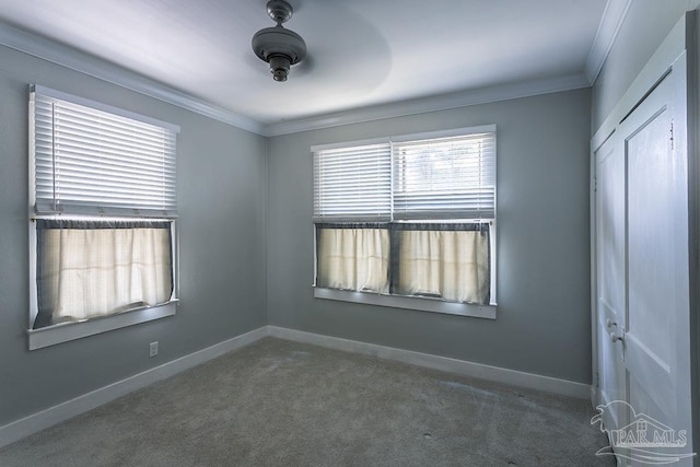 empty room featuring carpet floors, ornamental molding, and baseboards