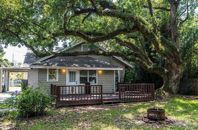 rear view of property featuring a fire pit, a wooden deck, and fence