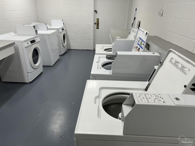 shared laundry area with concrete block wall and washer and dryer