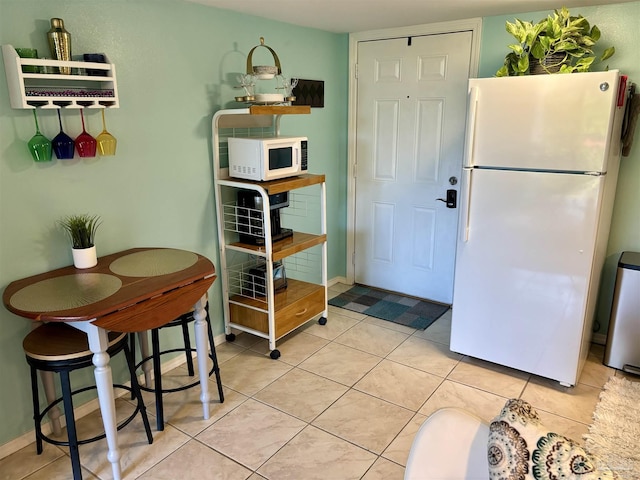 interior space featuring baseboards, white appliances, and light tile patterned flooring