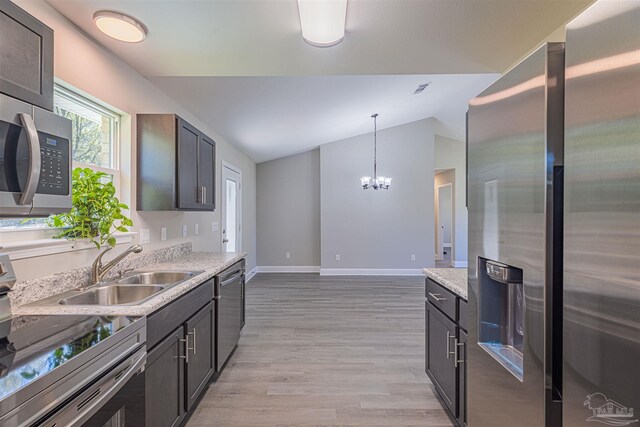 kitchen with lofted ceiling, light hardwood / wood-style flooring, pendant lighting, a notable chandelier, and stainless steel appliances