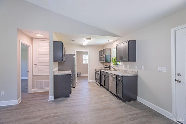 kitchen featuring light hardwood / wood-style floors, stainless steel appliances, light stone countertops, and lofted ceiling