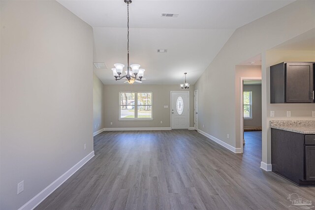 interior space with an inviting chandelier, vaulted ceiling, wood-type flooring, and a healthy amount of sunlight