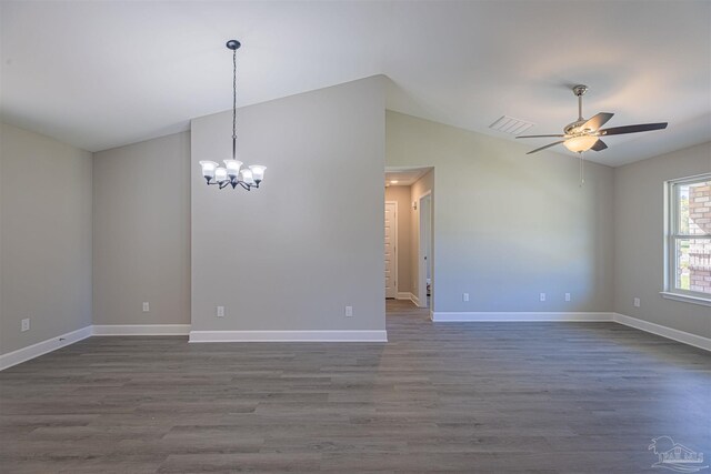 spare room with vaulted ceiling, ceiling fan with notable chandelier, and dark hardwood / wood-style flooring