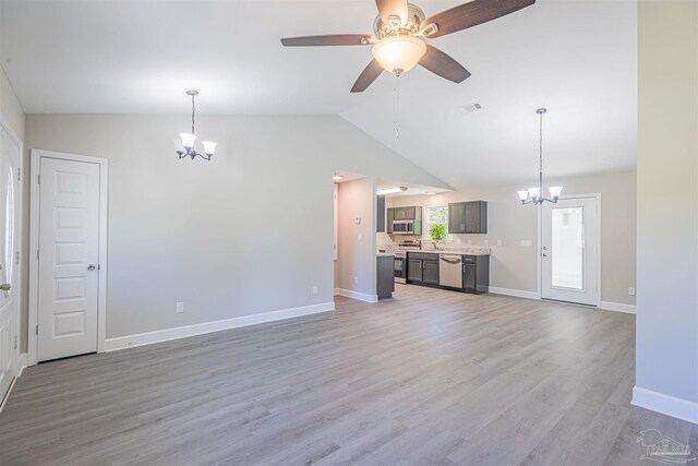 unfurnished living room featuring light hardwood / wood-style flooring, lofted ceiling, and ceiling fan with notable chandelier