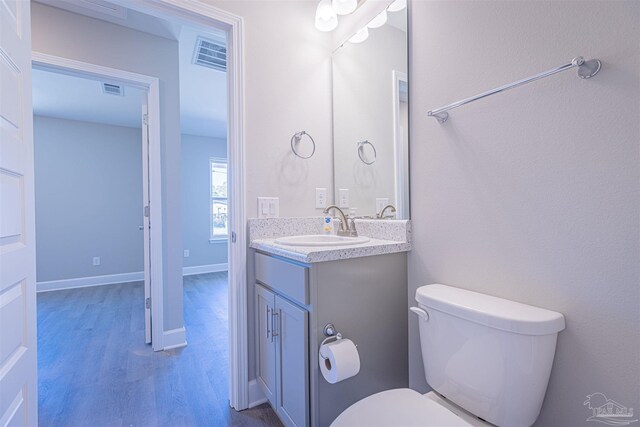 bathroom with toilet, vanity, and wood-type flooring