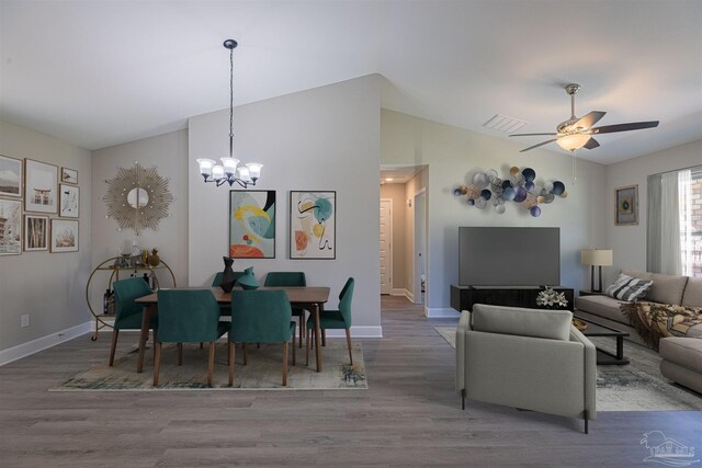 dining area with lofted ceiling, ceiling fan with notable chandelier, and hardwood / wood-style floors