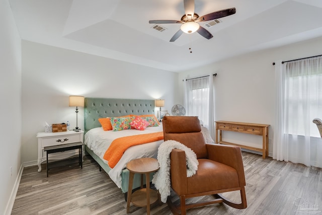 bedroom featuring a tray ceiling, ceiling fan, and light hardwood / wood-style flooring