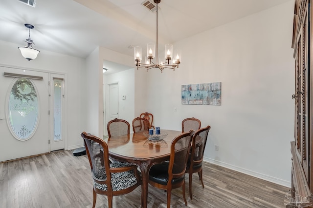 dining area with light hardwood / wood-style flooring and an inviting chandelier