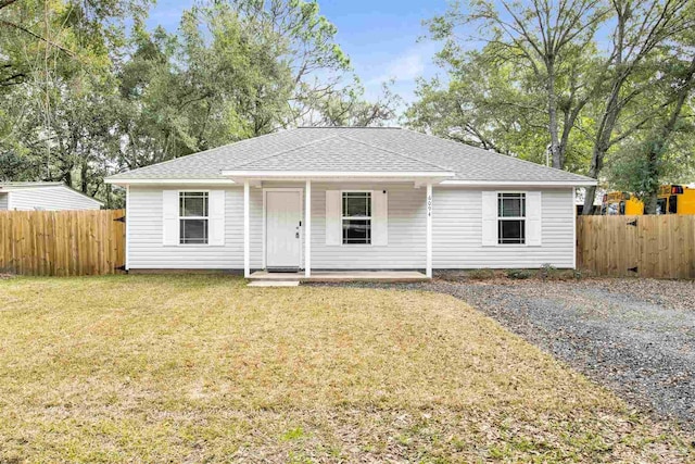 view of front of home with covered porch, fence, a front lawn, and roof with shingles