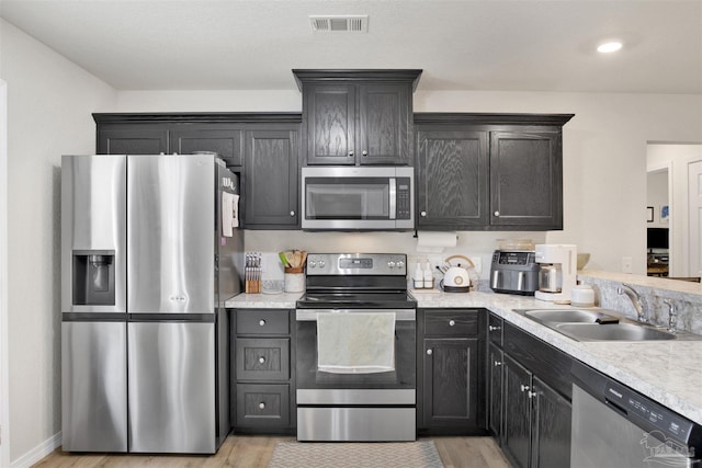 kitchen with light countertops, appliances with stainless steel finishes, a sink, and visible vents