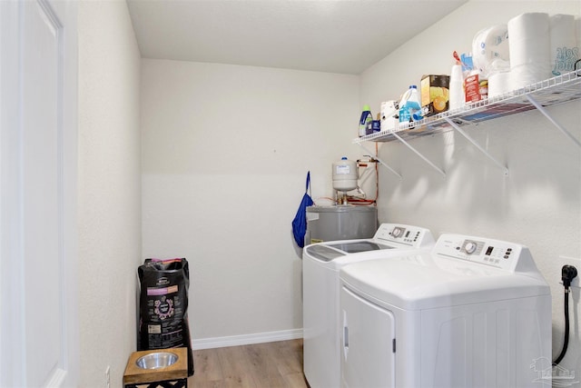 laundry area featuring light wood finished floors, water heater, washer and dryer, laundry area, and baseboards