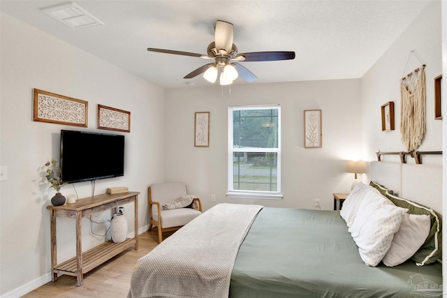 bedroom featuring light wood-style floors, baseboards, visible vents, and a ceiling fan