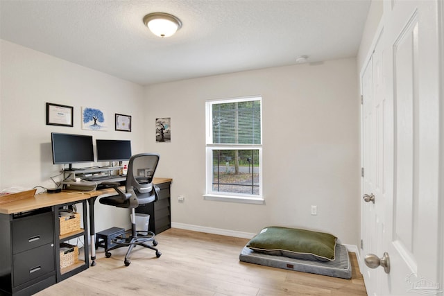 home office featuring light wood-type flooring, a textured ceiling, and baseboards