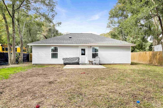 rear view of house featuring roof with shingles, a yard, a patio, and fence