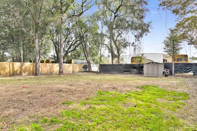 view of yard with an outbuilding, fence, and a shed