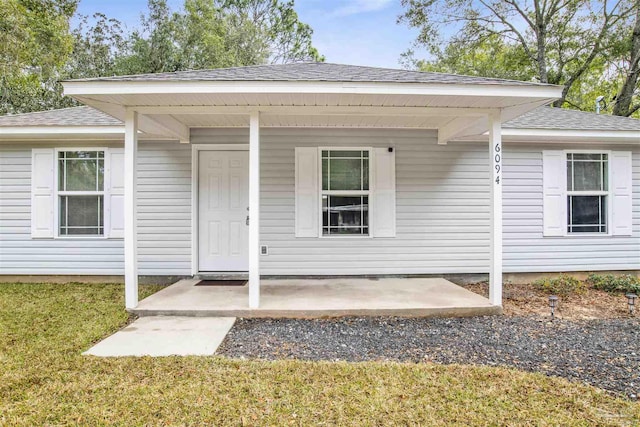 doorway to property with roof with shingles and a lawn