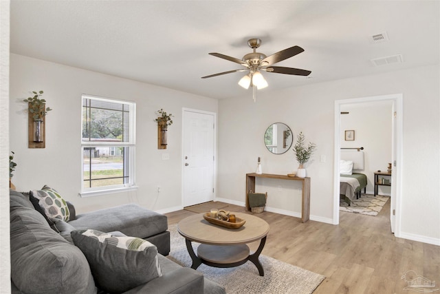 living room with light wood-type flooring, baseboards, and visible vents