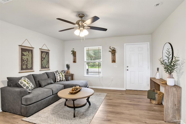 living area featuring light wood-style flooring, visible vents, ceiling fan, and baseboards