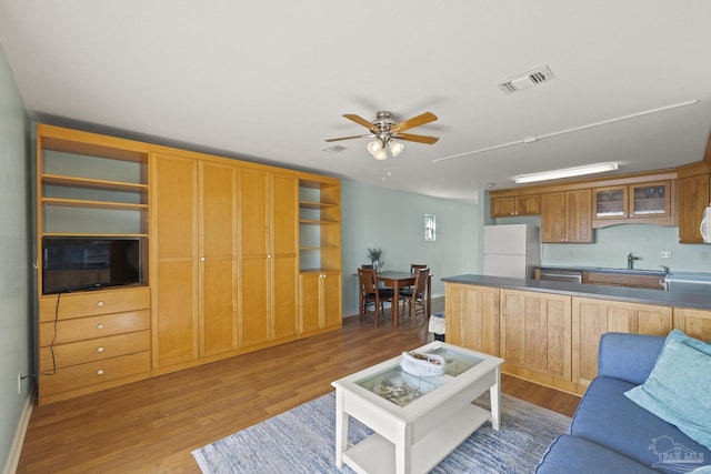 living room with ceiling fan, light hardwood / wood-style floors, and sink