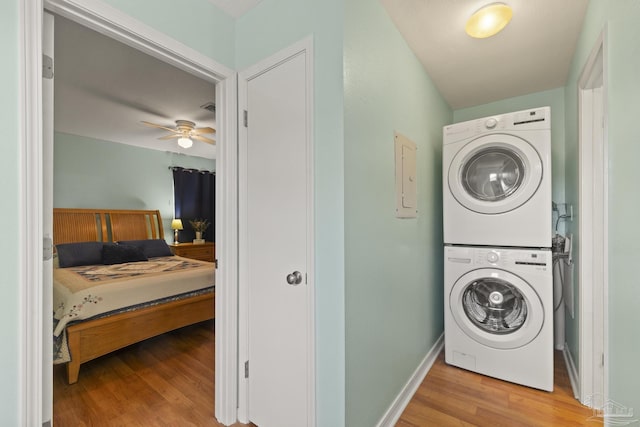 clothes washing area featuring light hardwood / wood-style floors, ceiling fan, and stacked washer / dryer