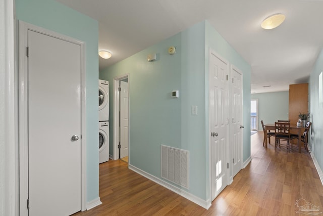 hallway with stacked washer / dryer and light hardwood / wood-style flooring