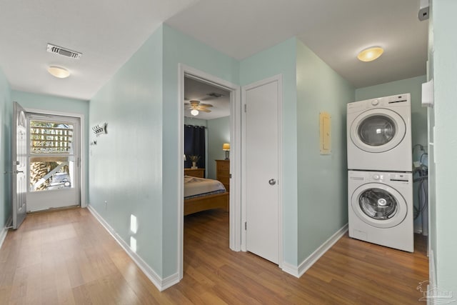 laundry room featuring ceiling fan, stacked washer / drying machine, and wood-type flooring