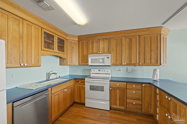 kitchen with white appliances, light hardwood / wood-style floors, and sink