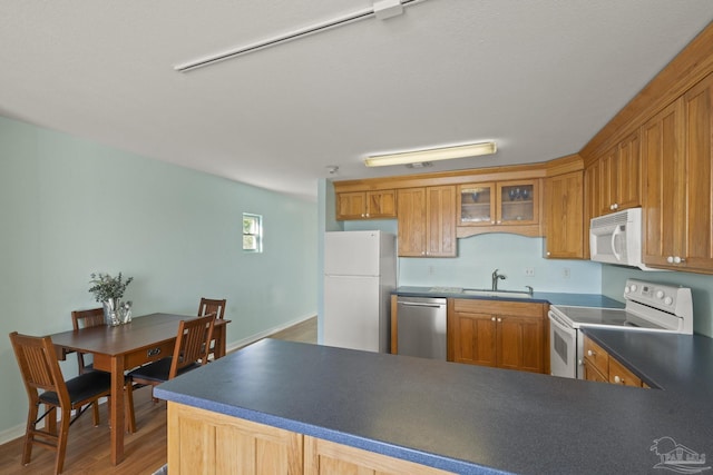 kitchen featuring sink, white appliances, hardwood / wood-style flooring, and kitchen peninsula