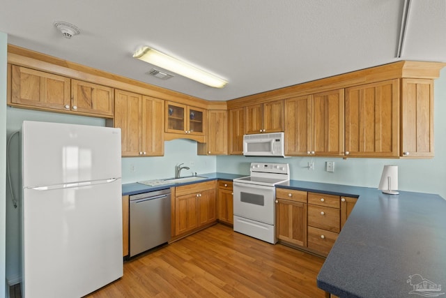 kitchen with white appliances, light hardwood / wood-style floors, and sink