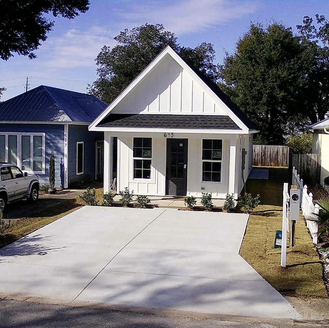 view of front of house featuring board and batten siding, roof with shingles, and fence